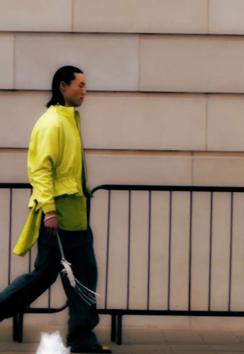 Blurred motion shot of a model in a bright lime jacket walking past a railing